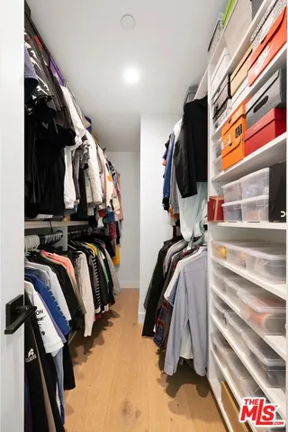 a view of walk in closet with clothes and shoes