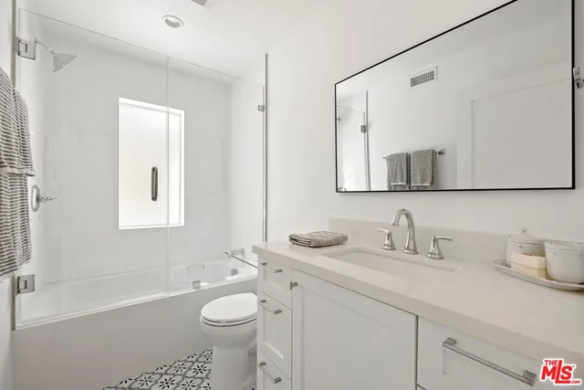 a bathroom with a toilet a sink a mirror a bathtub and vanity