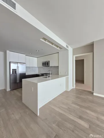 a large white kitchen with kitchen island a sink dishwasher a refrigerator and white cabinets next to a window