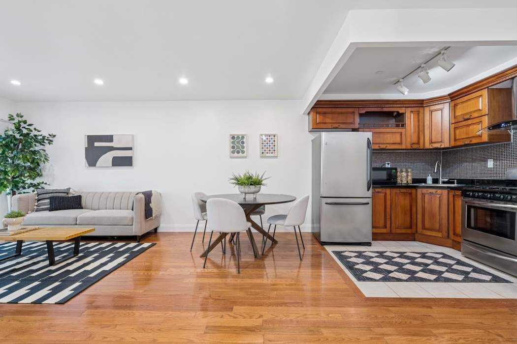 27-16 41st Avenue, Unit 3D Queens, NY 11101 - Photo 5 of 14 a kitchen with stainless steel appliances granite countertop a refrigerator a stove a sink dishwasher and a dining table with wooden floor