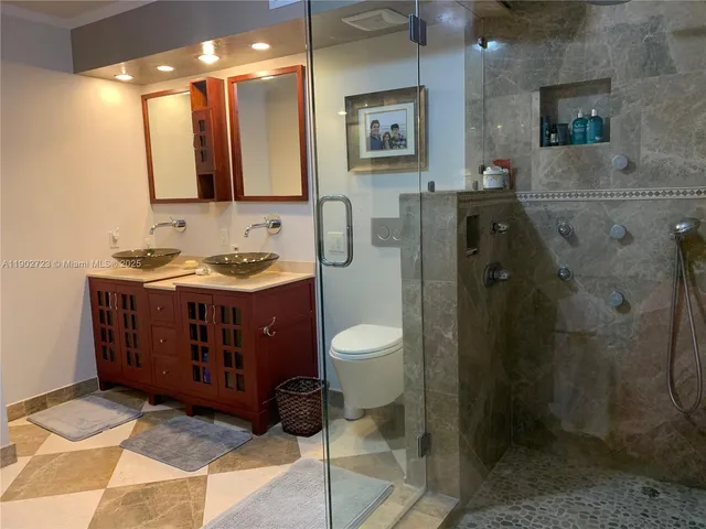 a bathroom with a double vanity sink toilet mirror and shower