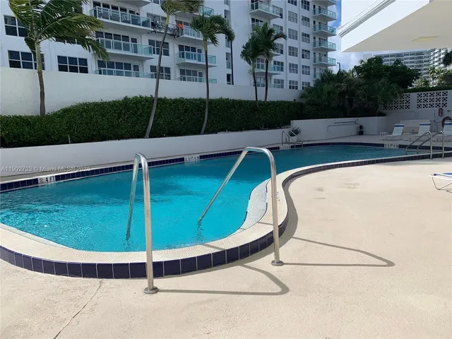 a view of a swimming pool with a yard and potted plants