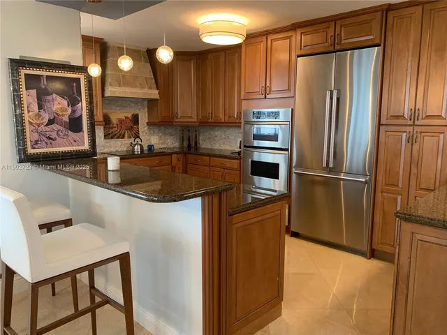 a kitchen with stainless steel appliances granite countertop a refrigerator a sink and a stove