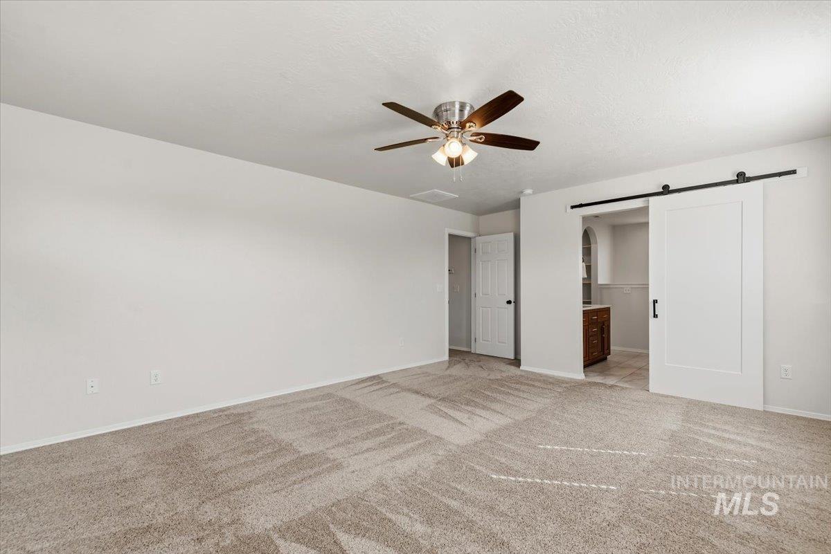 12310 West Hidden Point Drive Star, ID 83669 - Photo 14 of 48 Spacious carpeted room featuring a ceiling fan, white walls, and a contemporary barn door