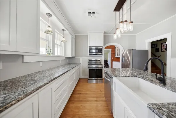 a large kitchen with granite countertop a sink dishwasher a stove and a dining table with wooden floor