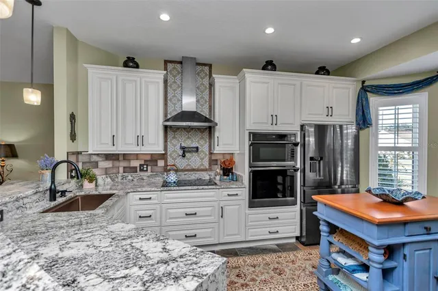 a kitchen with kitchen island granite countertop a stove a sink and a refrigerator