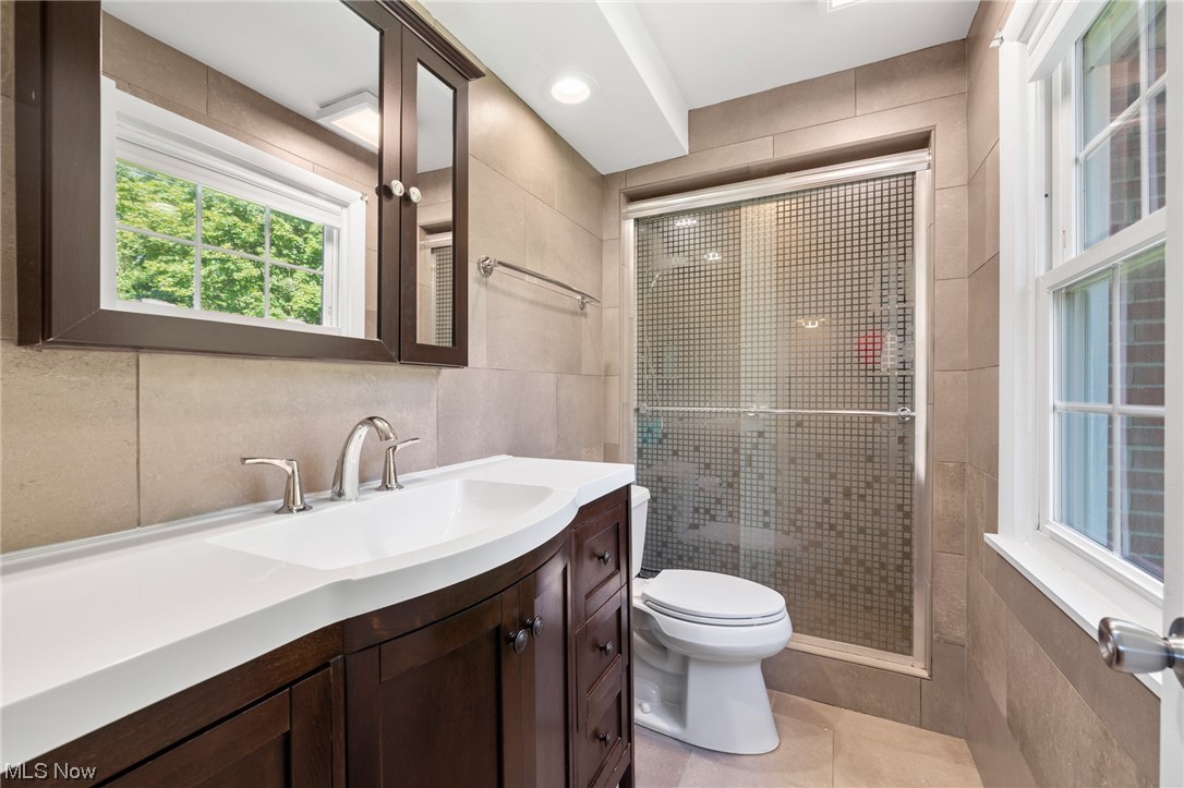 2685 Green Road Shaker Heights, OH 44122 - Photo 28 of 31 Primary Bathroom featuring a shower with shower door, mirror, light tile floors, vanity, and tile walls