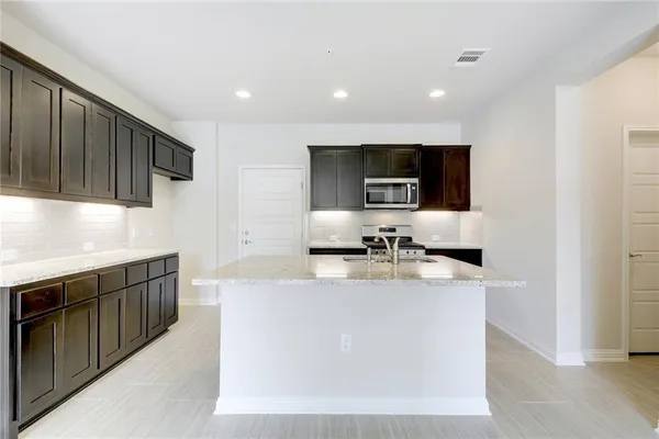 a kitchen with stainless steel appliances a sink a stove top oven a refrigerator and dishwasher