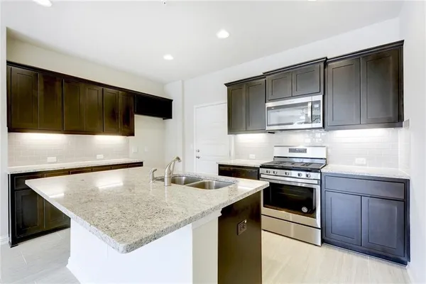 a kitchen with stainless steel appliances granite countertop a sink stove and microwave