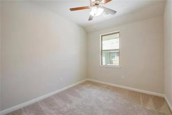 an empty room with a window and a chandelier fan