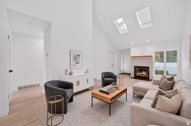 6969 South 855 East Midvale, UT 84047 - Photo 2 of 55 Vaulted ceiling living area featuring two skylights, a fireplace with decorative tile surround, wood-finish flooring, and white plantation shutters