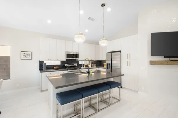 a kitchen with stainless steel appliances granite countertop a stove top oven a sink dishwasher a dining table and chairs with wooden floor