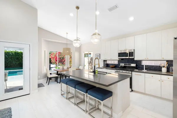 a kitchen with refrigerator a stove a dining table and chairs with wooden floor