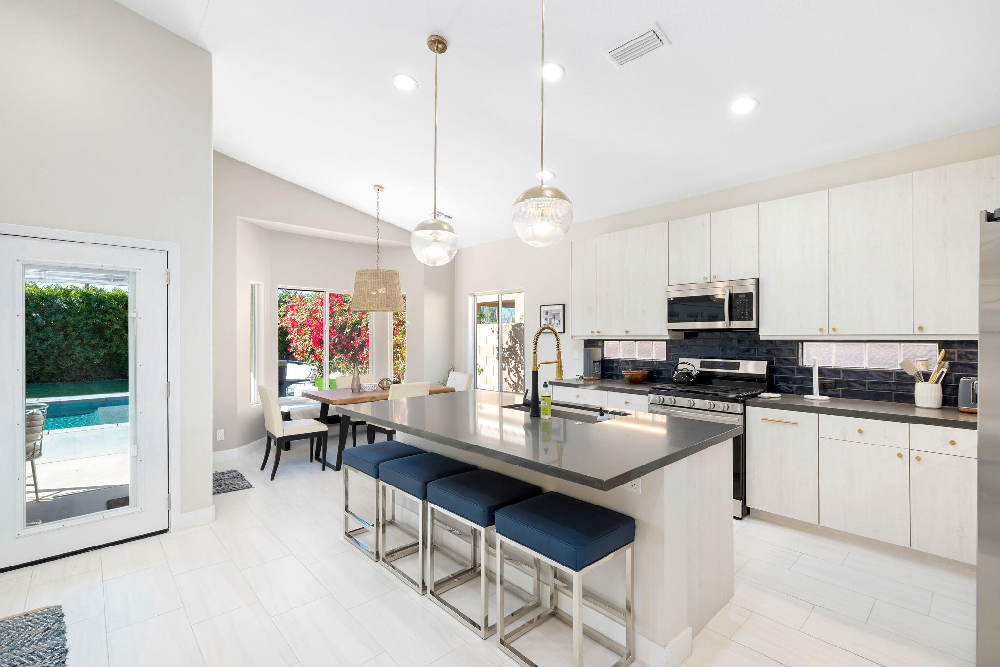 45809 Crosswater Street Indio, CA 92201 - Photo 19 of 48 a kitchen with stainless steel appliances granite countertop a stove top oven a sink dishwasher a dining table and chairs with wooden floor