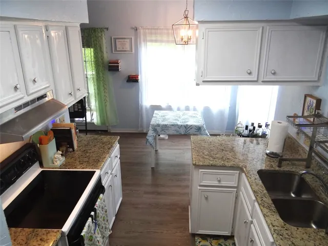 a kitchen with granite countertop a sink a stove and cabinets