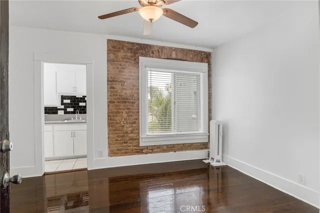 an empty room with wooden floor fan and windows