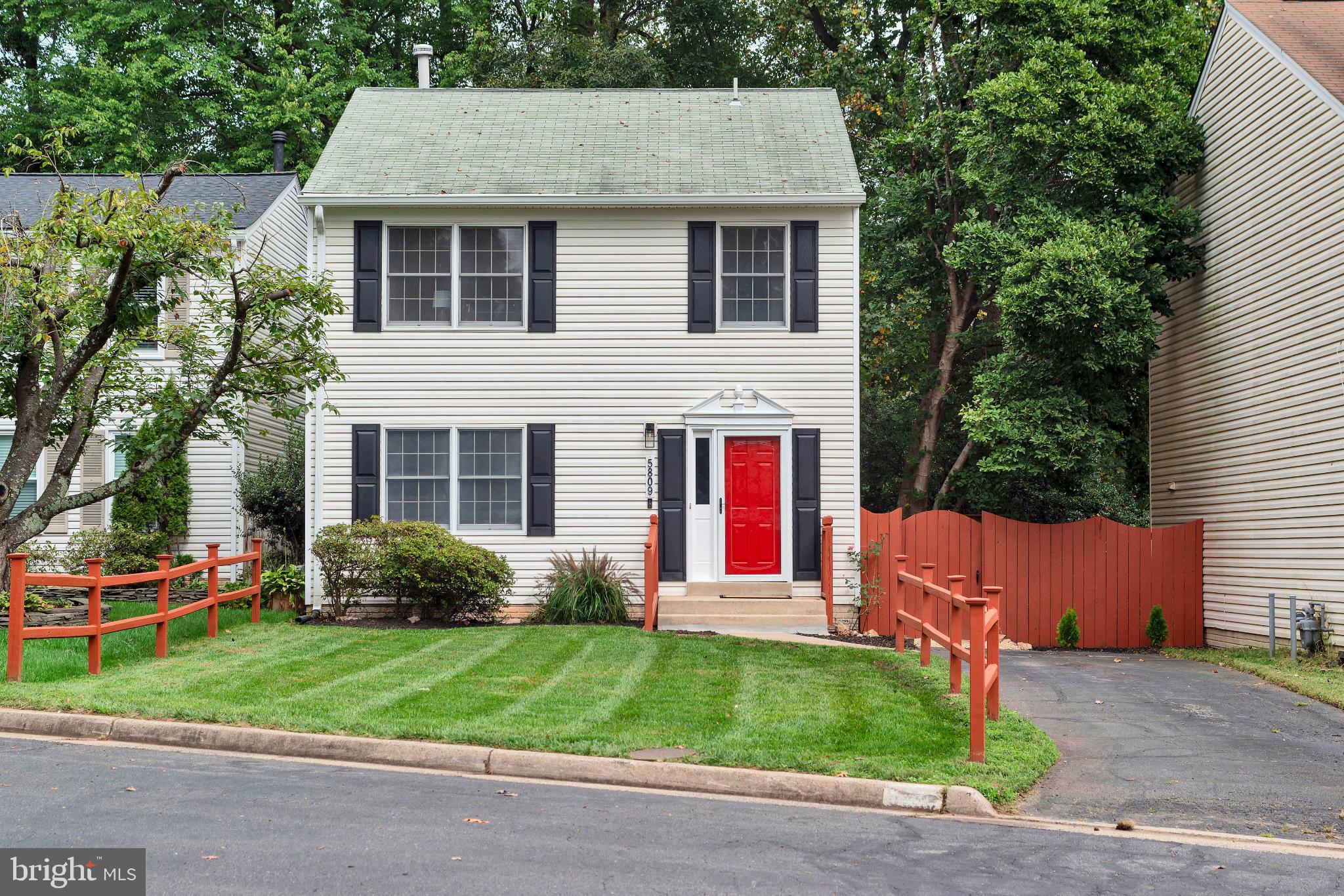 a view of a house with a yard plants and large tree