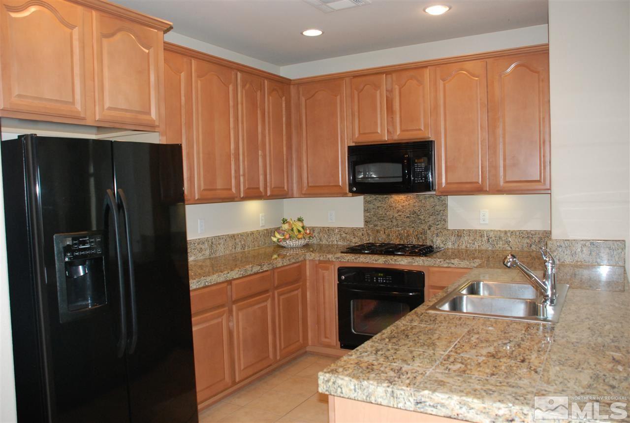1745 Wind Ranch Road, Unit A Reno, NV 89521 - Photo 1 of 1 a kitchen with granite countertop wooden cabinets and a stove top oven