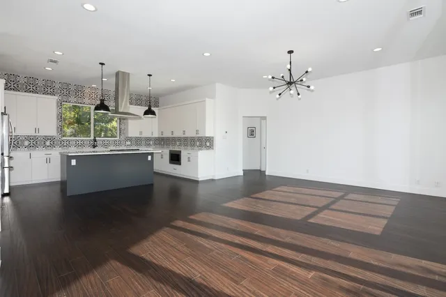 a kitchen with stainless steel appliances a sink a stove a refrigerator and white cabinets with wooden floor