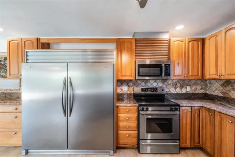 a kitchen with granite countertop a refrigerator and a stove top oven