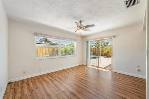a view of an empty room with a window and wooden floor