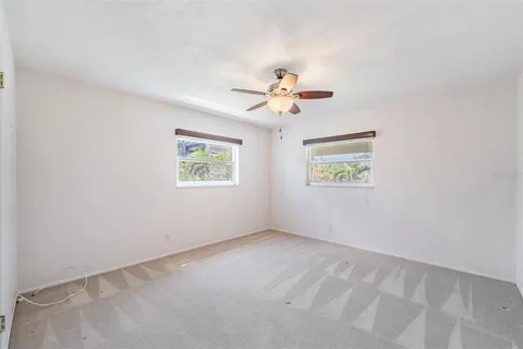 an empty room with windows and a fan