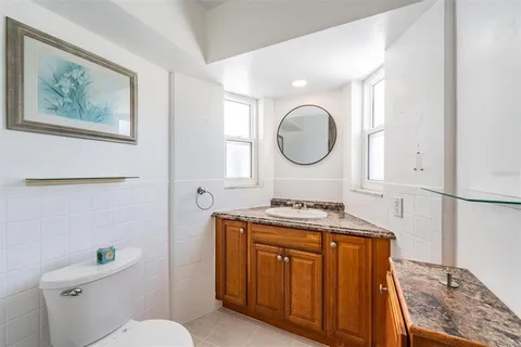 a bathroom with a granite countertop toilet sink and mirror