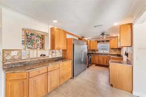 a kitchen with granite countertop a refrigerator a sink a stove top oven and cabinets