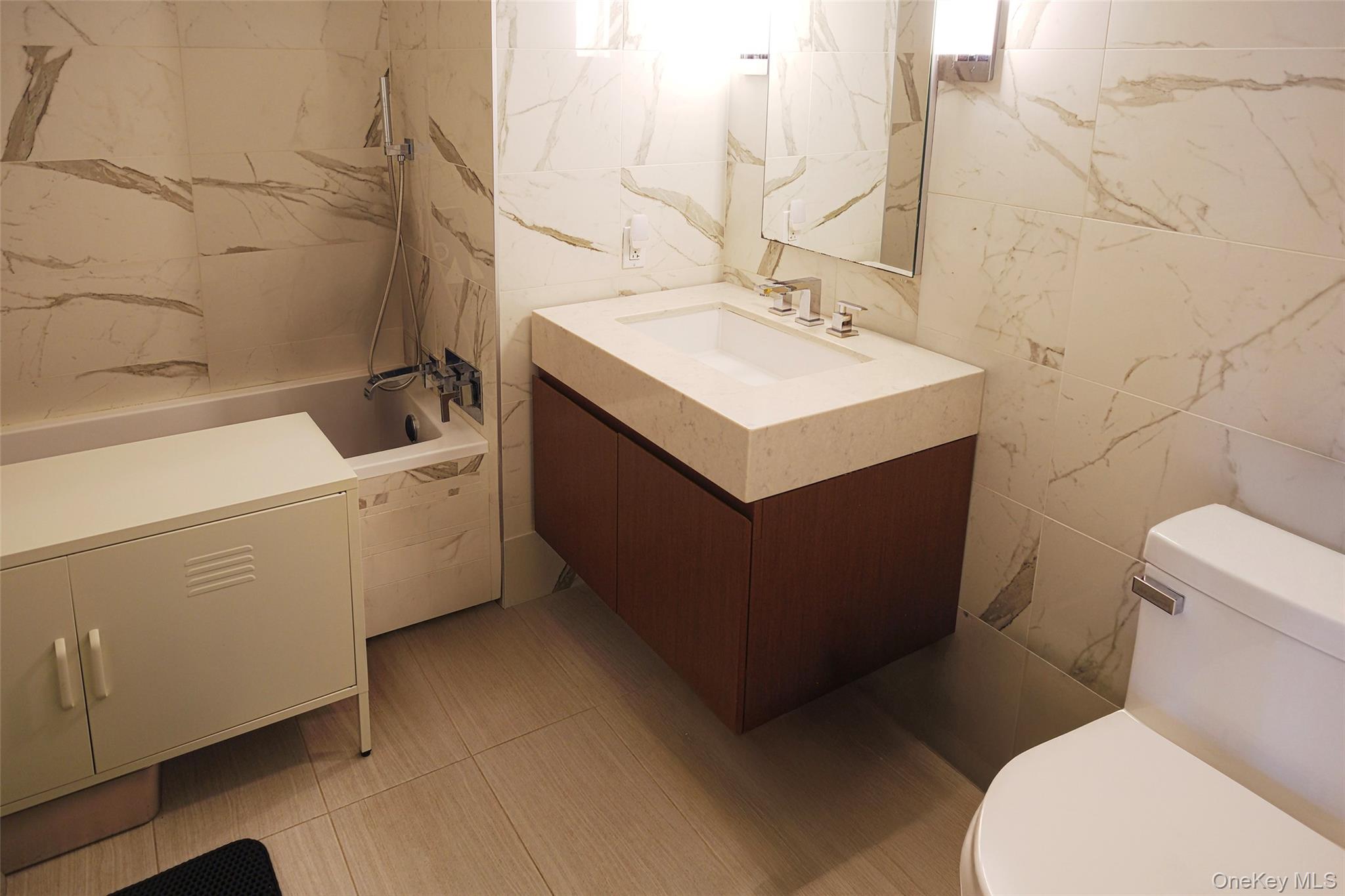 138-35 39th Avenue, Unit 12L Queens, NY 11354 - Photo 8 of 17 a bathroom with a sink mirror vanity and toilet