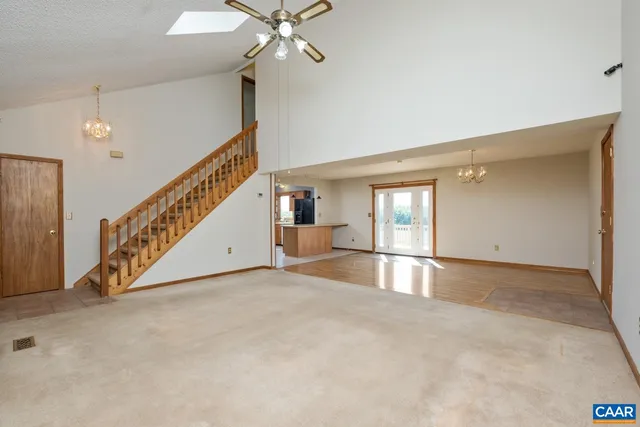 a view of an empty room with chandelier fan