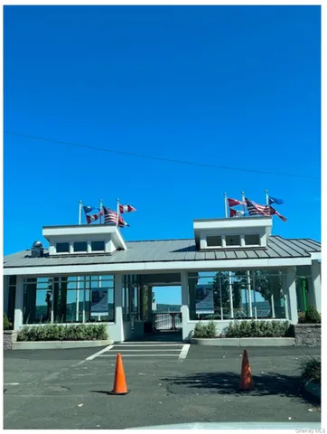 a front view of a white building with swimming pool and outdoor seating