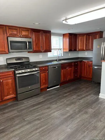 a kitchen with stainless steel appliances granite countertop a stove a sink and a microwave