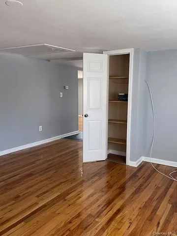 a view of an empty room with wooden floor and closet