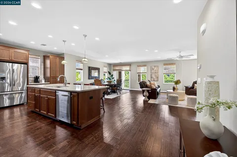 a living room with stainless steel appliances kitchen island granite countertop wooden floors and a view of living room