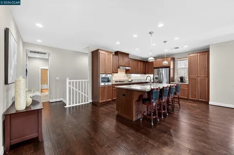 a kitchen with stainless steel appliances kitchen island granite countertop a table chairs and a refrigerator