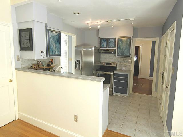 309 Cedar Street Raleigh, NC 27604 - Photo 9 of 25 Tiled-floor kitchen features, solid surface counters, stainless appliances, "streaky stained glass" cabinet doors and track lighting. Kitchen