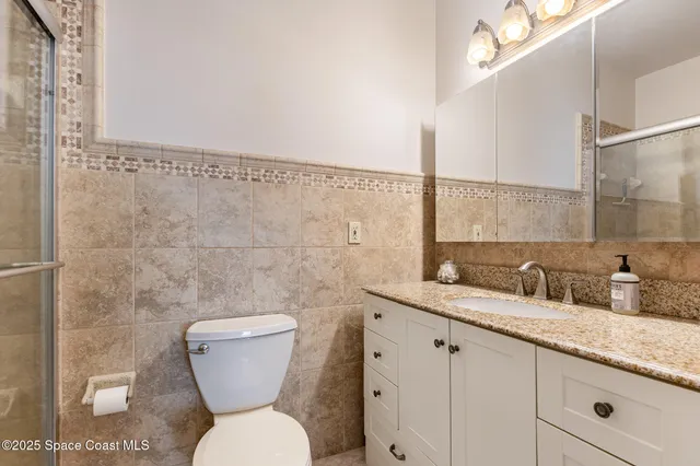 a bathroom with a granite countertop toilet sink and mirror