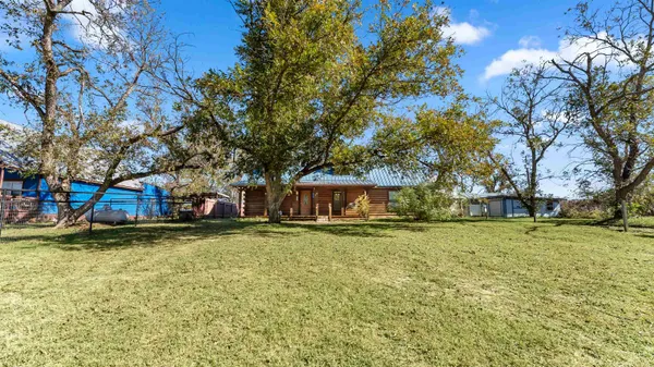 a view of a house with a yard and large trees
