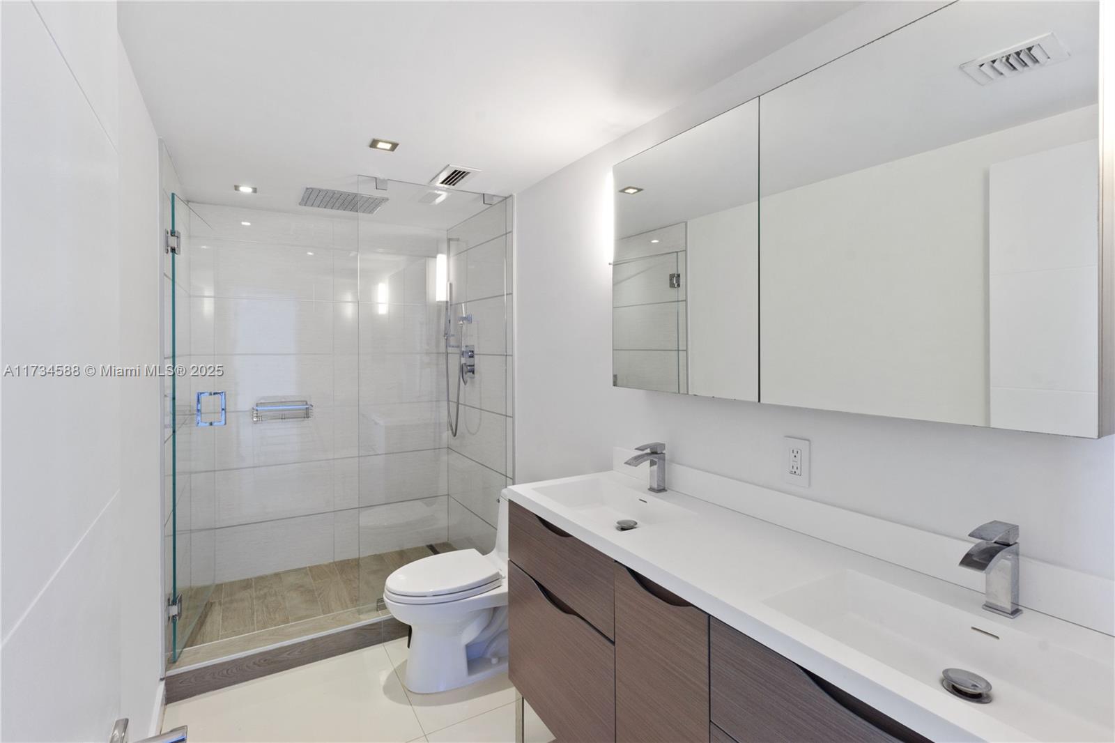 881 Ocean Drive, Unit 18F Key Biscayne, FL 33149 - Photo 7 of 12 a bathroom with a toilet sink a shower and mirror