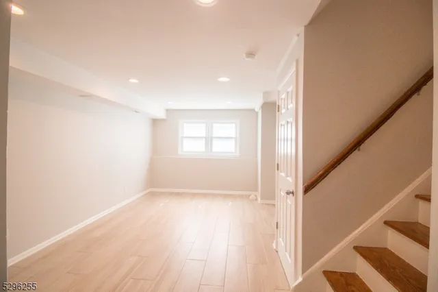 a view of an empty room with wooden floor and stairs