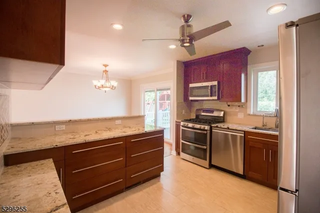 a kitchen with stainless steel appliances granite countertop stove top oven a sink dishwasher a dining table and chairs with wooden floor