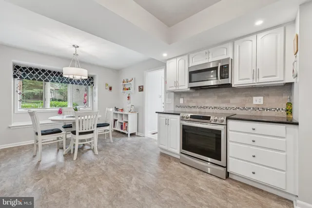 a kitchen with stainless steel appliances granite countertop a stove top oven a sink dishwasher a dining table and chairs with wooden floor