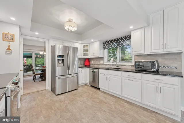 a kitchen with granite countertop a refrigerator sink and white cabinets