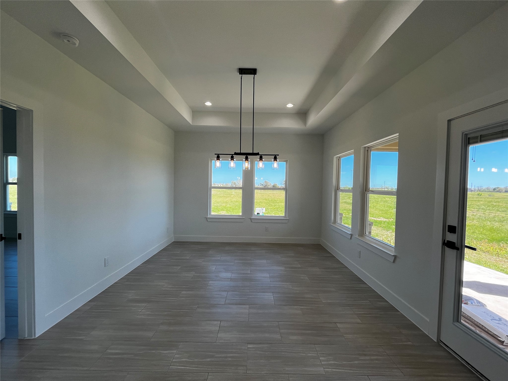471 Buffalo Trail Angleton, TX 77515 - Photo 16 of 35 Bright and airy room with large windows and a modern light fixture, featuring tile flooring and views of a green landscape. Ideal for a dining area.