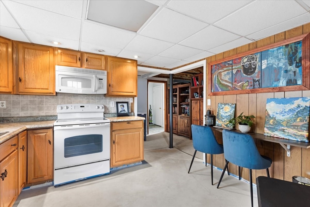 107 Ann Street Raynham, MA 02767 - Photo 25 of 34 a kitchen with stainless steel appliances kitchen island granite countertop a table chairs in it and wooden floors
