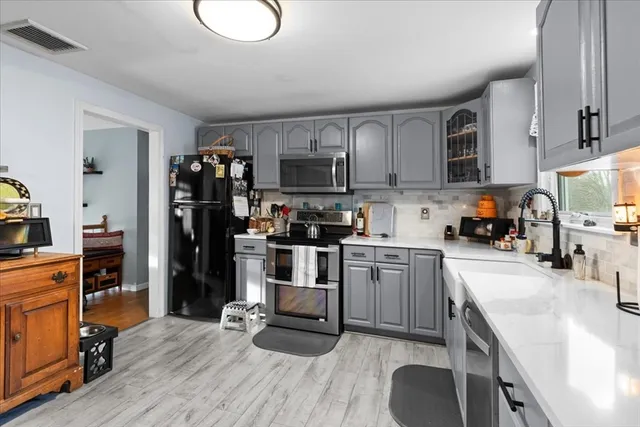 a kitchen with granite countertop a refrigerator stove top oven and sink
