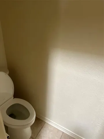 a white toilet sitting next to a white wall