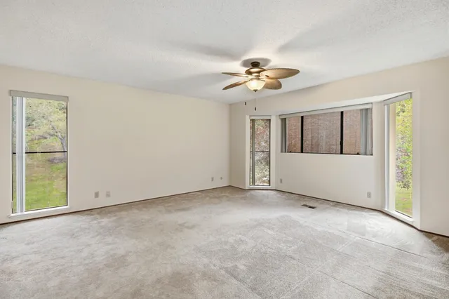an empty room with windows and chandelier fan