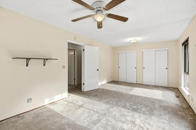 an empty room with closet and a ceiling fan