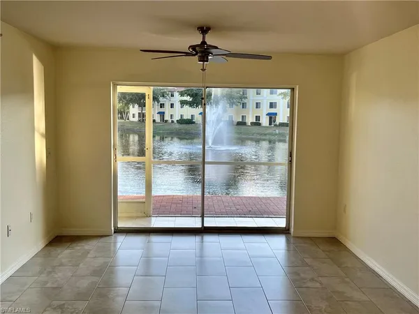 a view of an empty room with window and a kitchen
